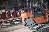 Digital blueprints on laptop in steel mill
