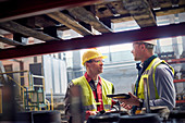 Steelworkers with tablet talking in steel mill