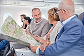 Mature friends looking at map on airplane