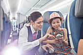 Flight attendant helping girl passenger