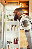 Young man peering into refrigerator