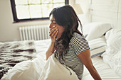 Tired woman yawning in bed