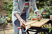 Woman with tape measure measuring wood on patio