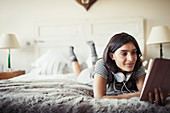 Woman relaxing on bed, using digital tablet