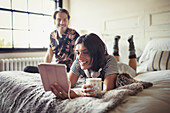 Smiling couple relaxing, using tablet