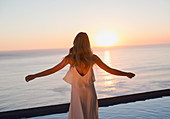Woman with arms outstretched watching sunset