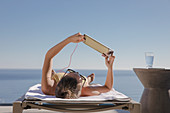 Woman sunbathing, using digital tablet
