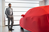 Portrait car salesman next to covered car