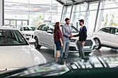 Car salesman and customers handshaking in showroom