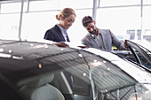 Car salesman showing car to customer in showroom