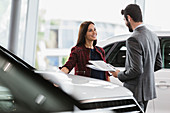 Car saleswoman showing brochure to customer