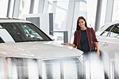 Portrait customer browsing cars in showroom