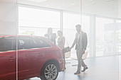 Car salesman showing car to customers in showroom