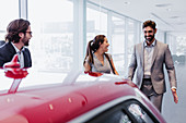 Car salesman and couple customers looking at car