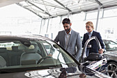 Car saleswoman showing car to customer in showroom