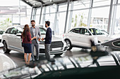 Car salesman talking to couple customers