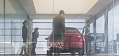 Car sales people and customers looking at car