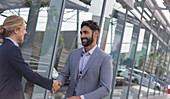 Car salesman greeting, shaking hands with customer