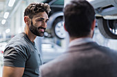 Smiling auto mechanic talking to customer