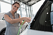 Portrait customer charging hybrid car in showroom