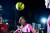 Young soccer player heading the ball at night