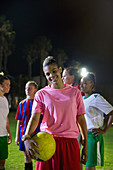 Portrait young soccer player with ball at night