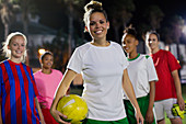 Portrait young soccer team with ball at night