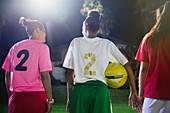 Young soccer players with ball talking at night