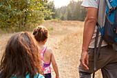 Father and daughters hiking on sunny path