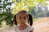 Portrait wide-eyed girl with pigtails in yard