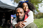 Portrait smiling father piggybacking daughter