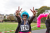 Portrait runner in wig gesturing peace sign