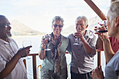 Active senior friends drinking wine on balcony
