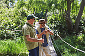 Active senior men friends fishing on footbridge
