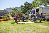 Active senior friends relaxing outside camper van