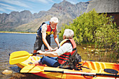 Active senior couple kayaking on sunny summer lake
