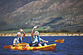 Portrait active senior couple in kayak waving