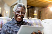 Portrait smiling, senior man using tablet on sofa