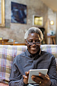 Smiling senior man using digital tablet on sofa
