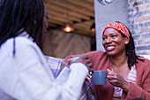 Smiling women friends talking and drinking coffee