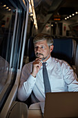 Businessman working at laptop on train