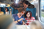 Young friends looking at photographs on train
