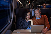 Couple using digital tablet on dark train at night
