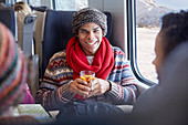 Smiling young man drinking mulled wine on train