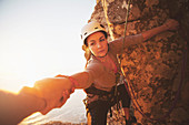 Focused female rock climber reaching for arm