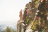 Rock climbers climbing rocks above sunny ocean
