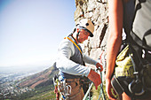 Male rock climber adjusting ropes
