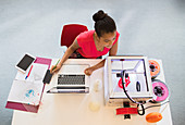 Female designer at laptop watching 3D printer