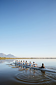 Female rowers rowing scull on tranquil lake