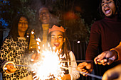 Playful girl with sparkler celebrating with family